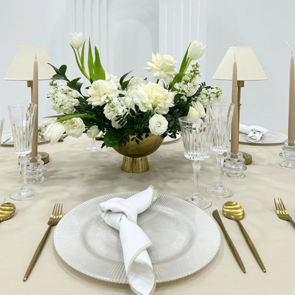 Sand Elegance- Dining Setup featuring a flower centerpiece, gold cutlery, wine glasses, and napkins arranged on a table for eight guests.