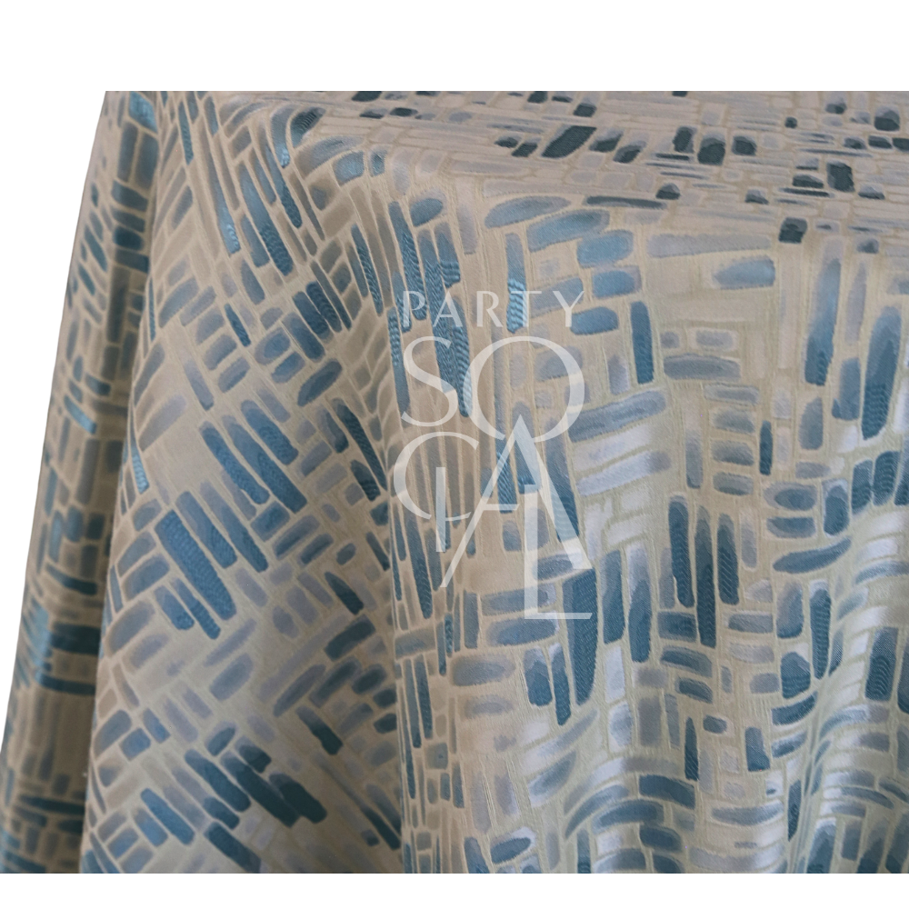 Blue Mosaic Tablecloth draped on a round table, showcasing a jacquard-style abstract pattern in slate blues, ideal for coastal-themed events by Party Social.