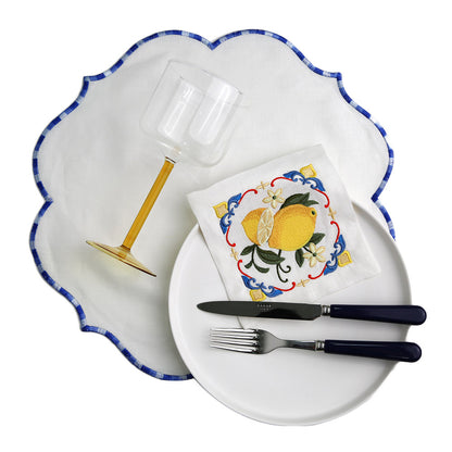 A Majolica Lemon Pure Linen Coaster with a plate, glass, and knife on it.