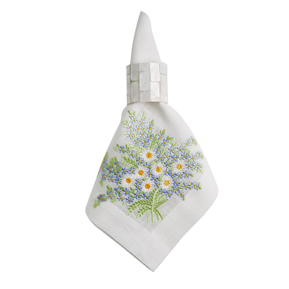 A white linen dinner napkin with an embroidered floral design.