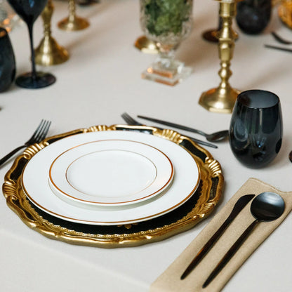 Elegant table setting from The Midnight Majlis Collection, featuring black-handled cutlery, gold-rimmed white plates on a gold charger, and black glassware amid modern decor.