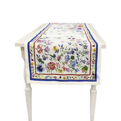 Vibrant Primrose Pure Linen Runner on a white table, featuring colorful floral prints with red and blue borders, perfect for enhancing any event setting.