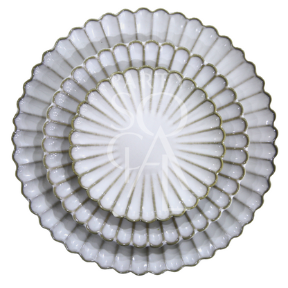 SCALLOPED LIKE PLATES: Three elegantly stacked white ceramic plates with scalloped, fluted rims, embodying a shell-like design for sophisticated dining occasions.