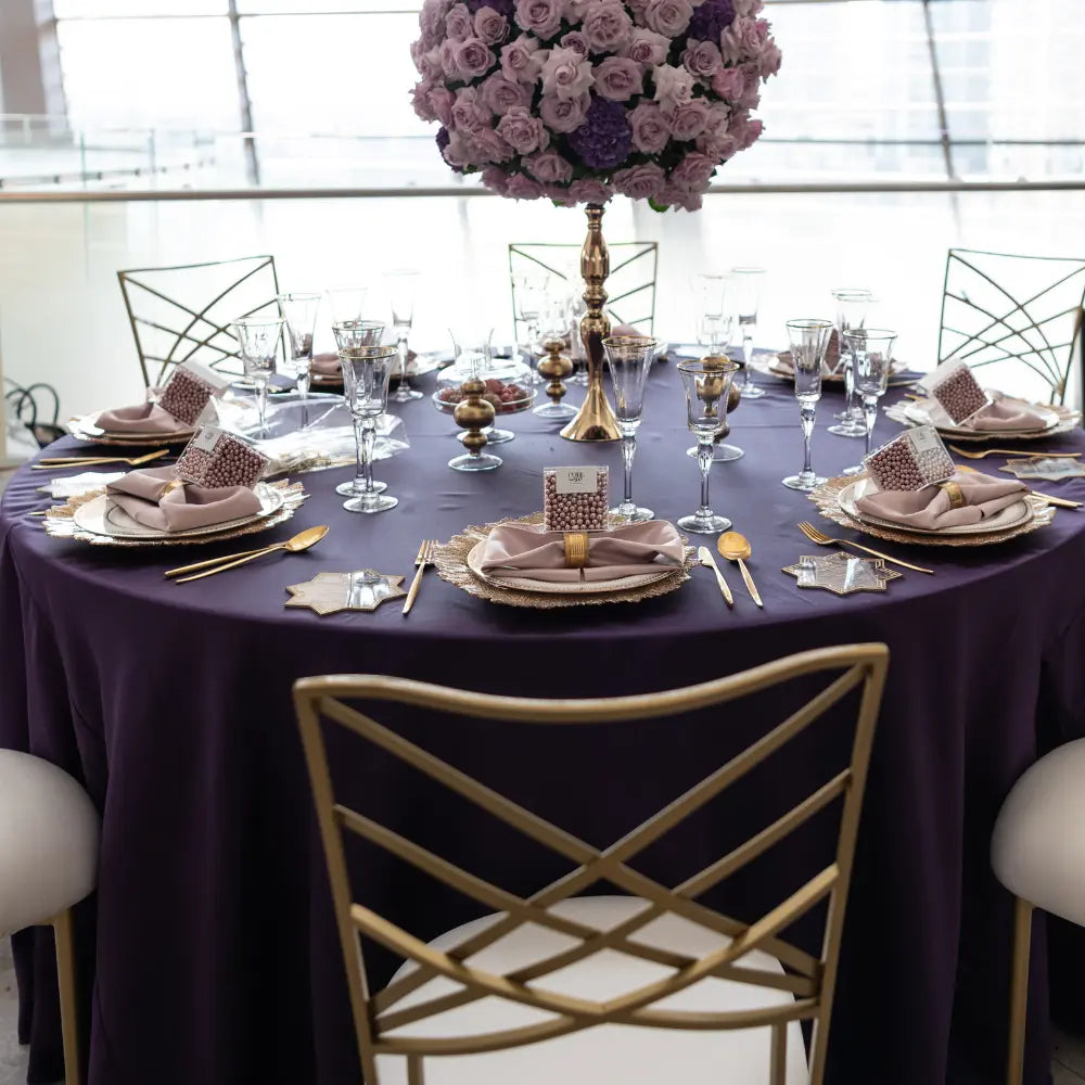 Round Satin Tablecloth elegantly drapes a formal setting with gold accents, crystal stemware, and a lavender centerpiece, ideal for sophisticated occasions.