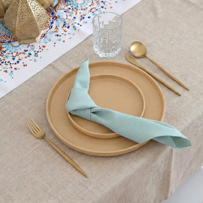 Golden Hour Iftar-Dining Setup: Elegant table setting with clay-hued plates, teal napkin, gold cutlery, and decorative lanterns, perfect for an 8-guest dinner party.