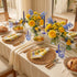 Elegant dining table setting with floral arrangements, lemons, and bread.