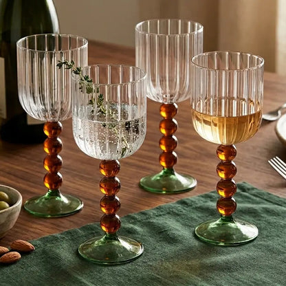 Set of four decorative wine glasses on a table with food and bread.