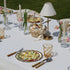 Amber Spiral Colored Acrylic Glass - Set of 4: Amber-swirled acrylic tumblers set on a spring-themed table with sunflower plates and pink-white tulip vases. Ideal for stylish outdoor dining.
