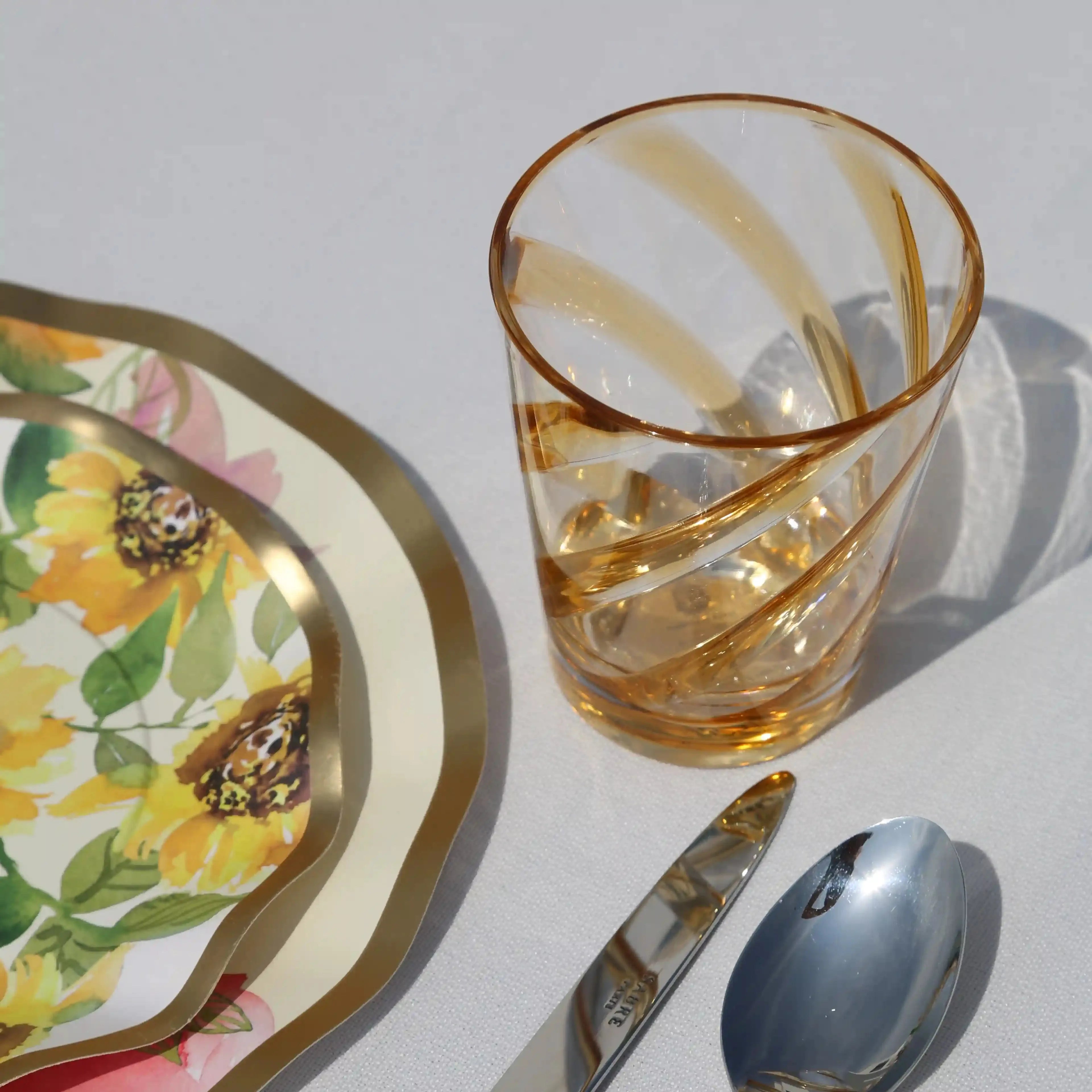 Amber Spiral Colored Acrylic Glass - Set of 4, featuring a stylish amber swirl pattern, part of an elegant tabletop setting with polished cutlery on a white tablecloth.