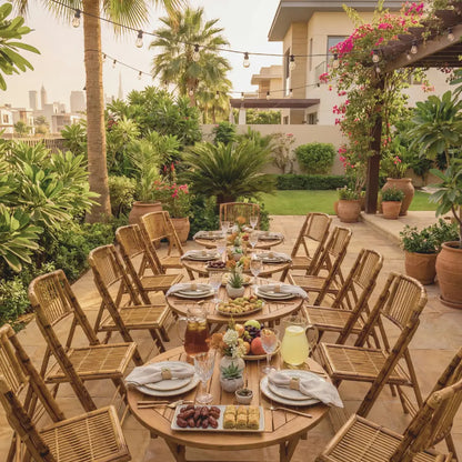Bamboo Folding Chairs surround a garden patio table, set with stoneware, glassware, and fruit platters, under string lights, showcasing Party Social&
