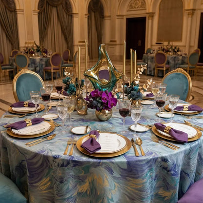 BLUE BRUSHED ROUND TABLECLOTH elegantly drapes a banquet table with teal, blue, and gold swirls, complemented by gold accents and luxurious crystal glassware in a formal setting.
