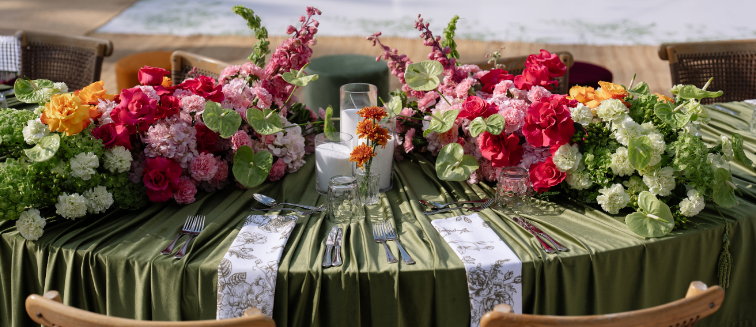 Green velvet decorative table setting with floral arrangements and green tablecloth.