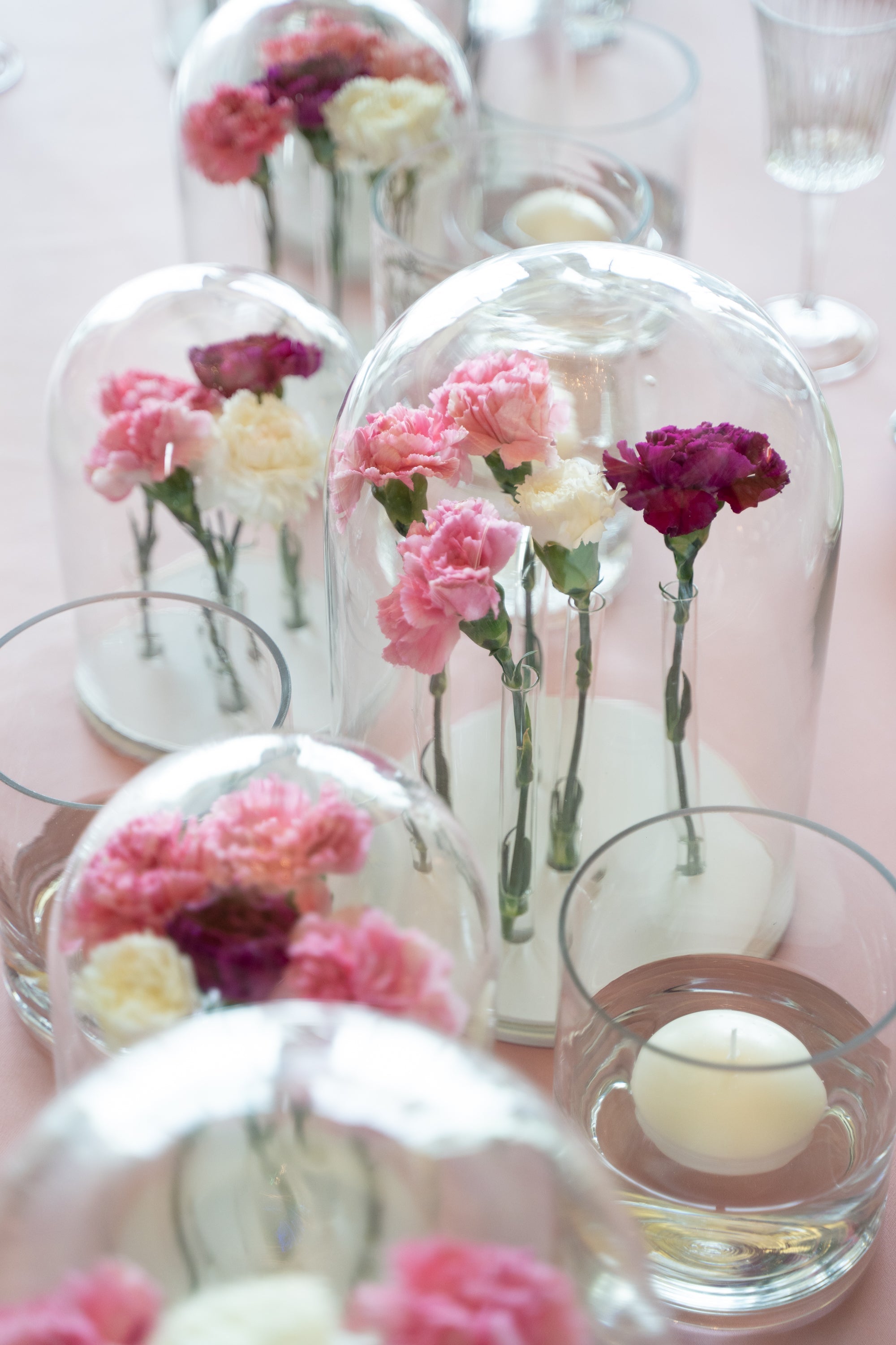 Bell jars with flowers under a glass dome on a wooden base, ideal for event centerpieces. Available in various sizes for versatile display.