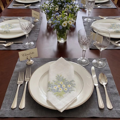 Daisy Pure Linen Dinner Napkin set features two white linen napkins with embroidered daisy sprays, ideal for elegant table settings at special events.