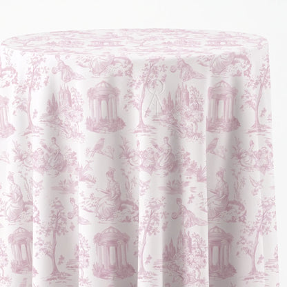A round table covered with a white tablecloth featuring a light pink classic toile de Jouy pattern with figures, trees, and classical architecture.