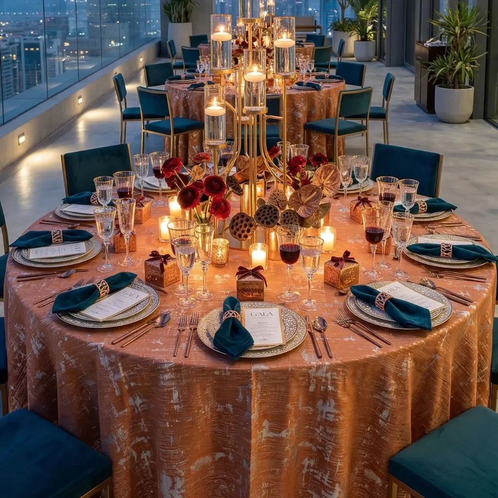 Burnt Orange Jacquard Round Tablecloth elegantly drapes a round table, set with gold chargers, teal napkins, and a gold candelabra for a formal banquet.