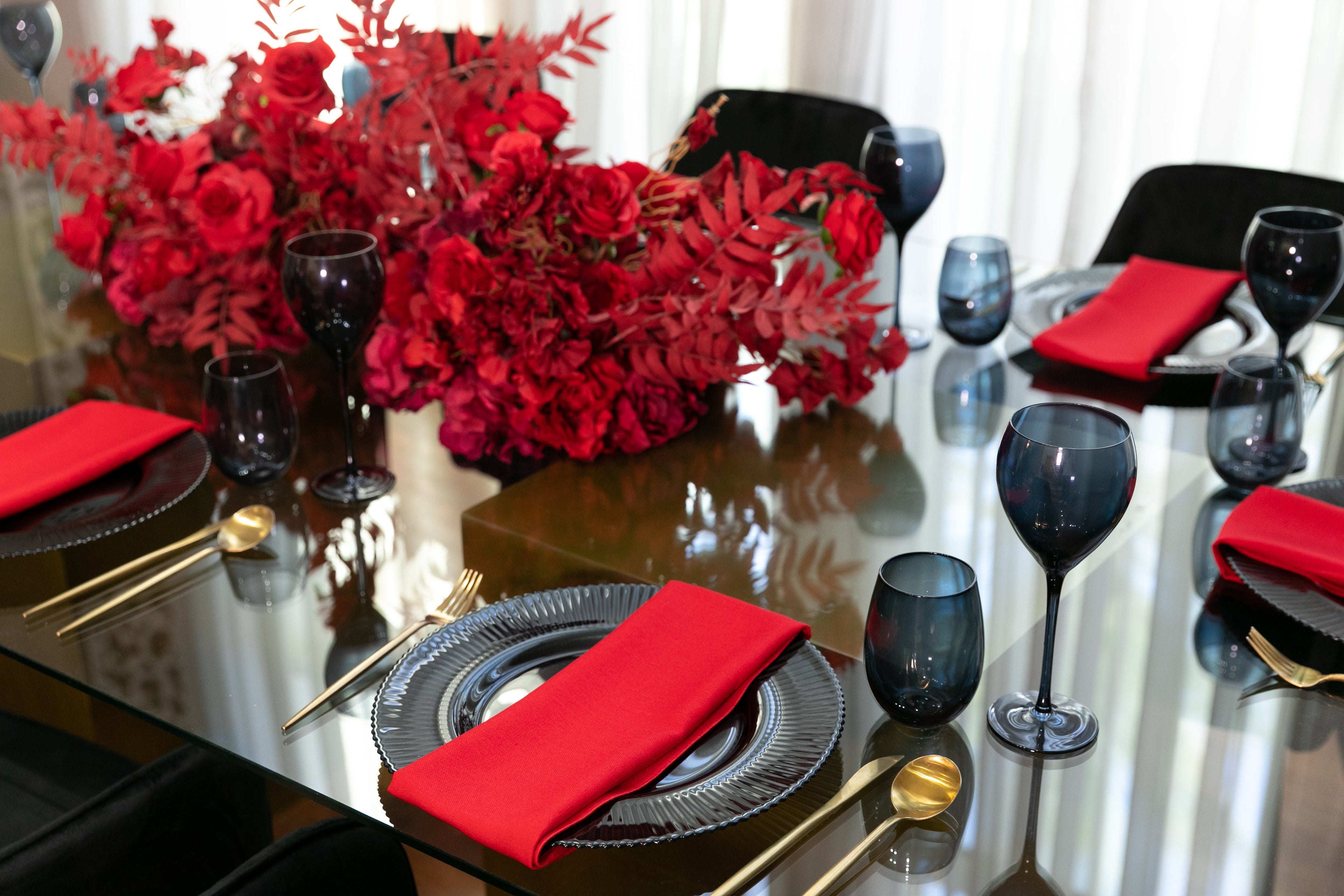 Black &amp; Gold Collection table setup featuring a red floral centerpiece, wine glasses, and tableware, designed for an elegant party of eight.