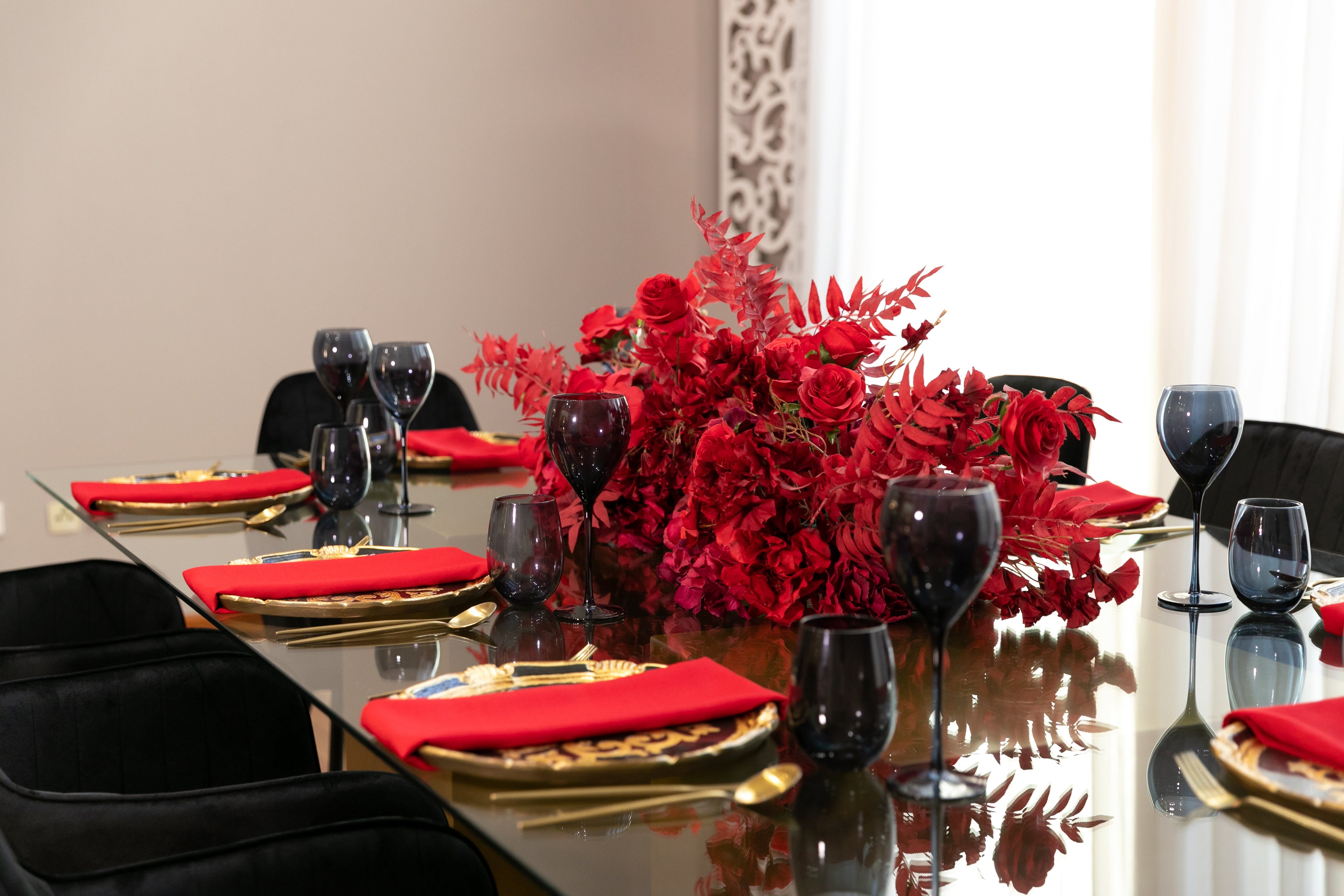 Black &amp; Gold Collection party setup featuring a table with red flowers, wine glasses, and elegant tableware, ideal for a stylish gathering of eight.