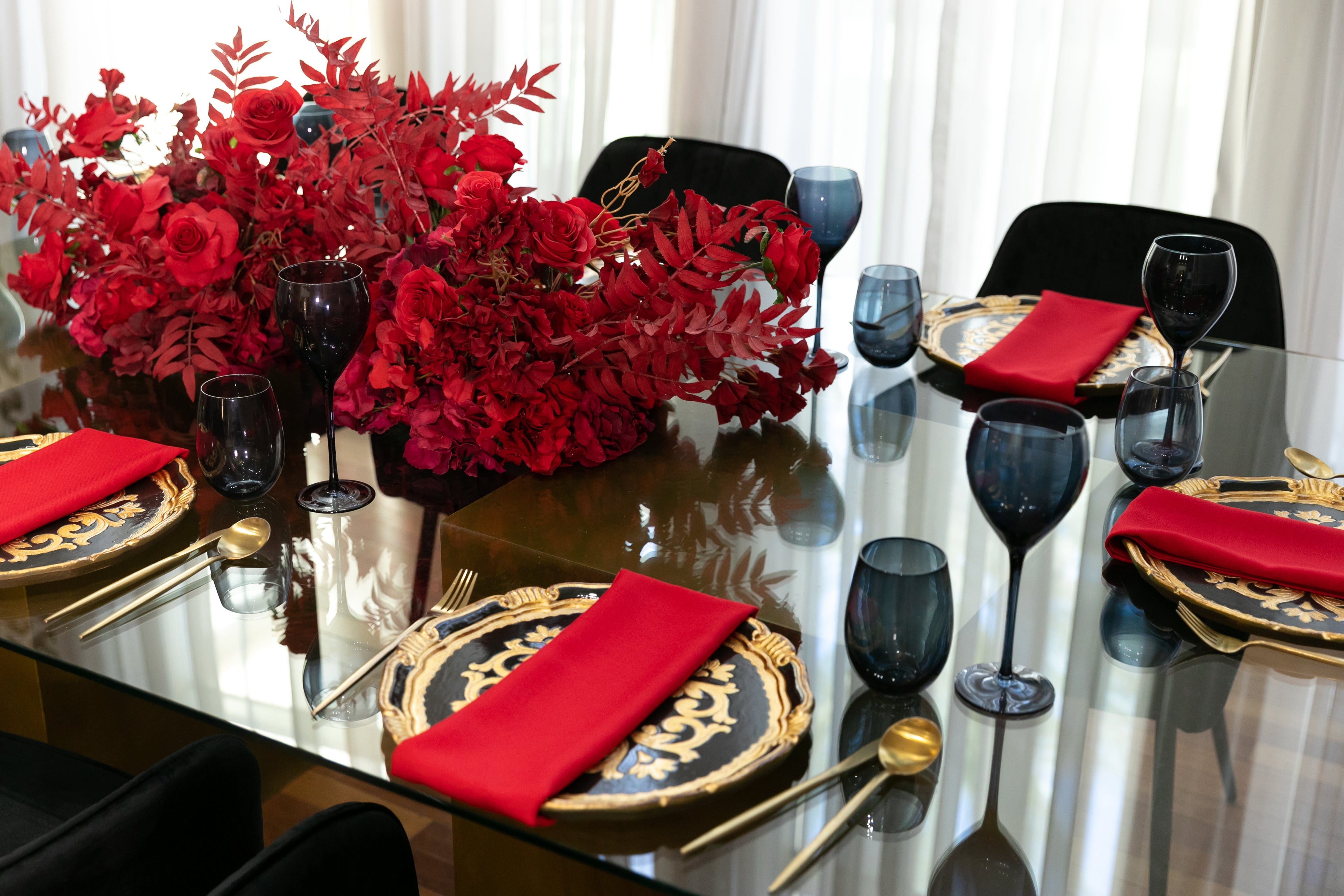 Black &amp; Gold Collection table setup featuring a red-napkin centerpiece, wine glasses, and floral arrangement, ideal for an elegant party of eight.