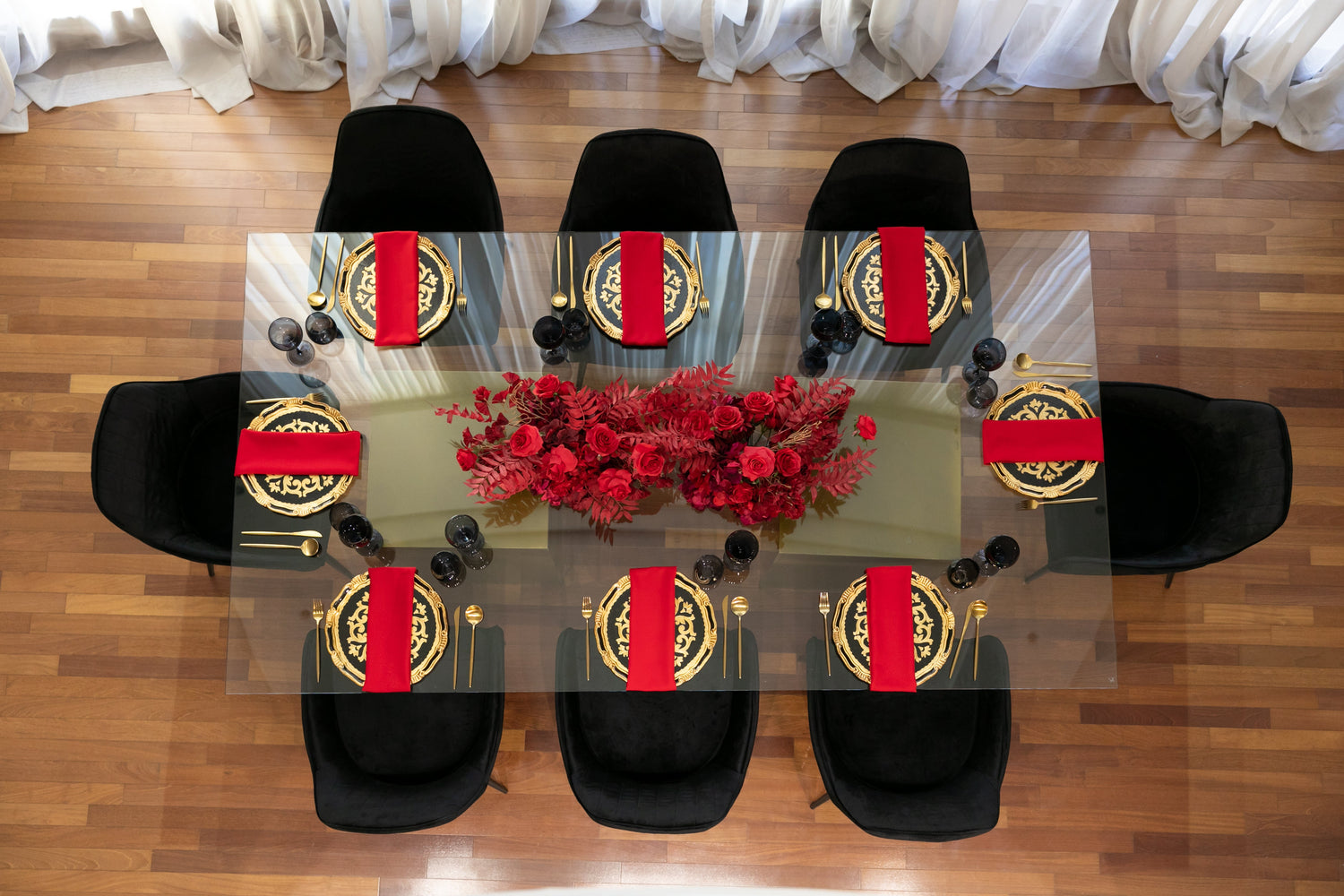 Black &amp; Gold Collection table setup featuring elegant plates, red napkins, and floral centerpieces, designed for hosting an unforgettable event for eight guests.