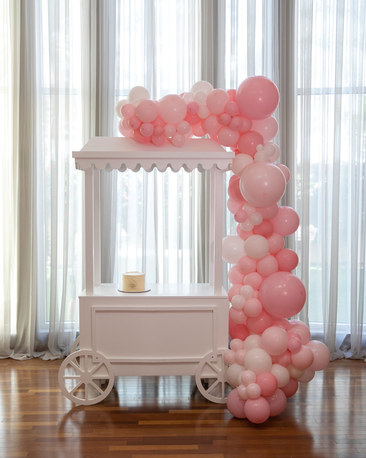 White Dessert Cart displayed indoors with a cake on top, set amidst a party-themed balloon arch, ideal for event decor or props.