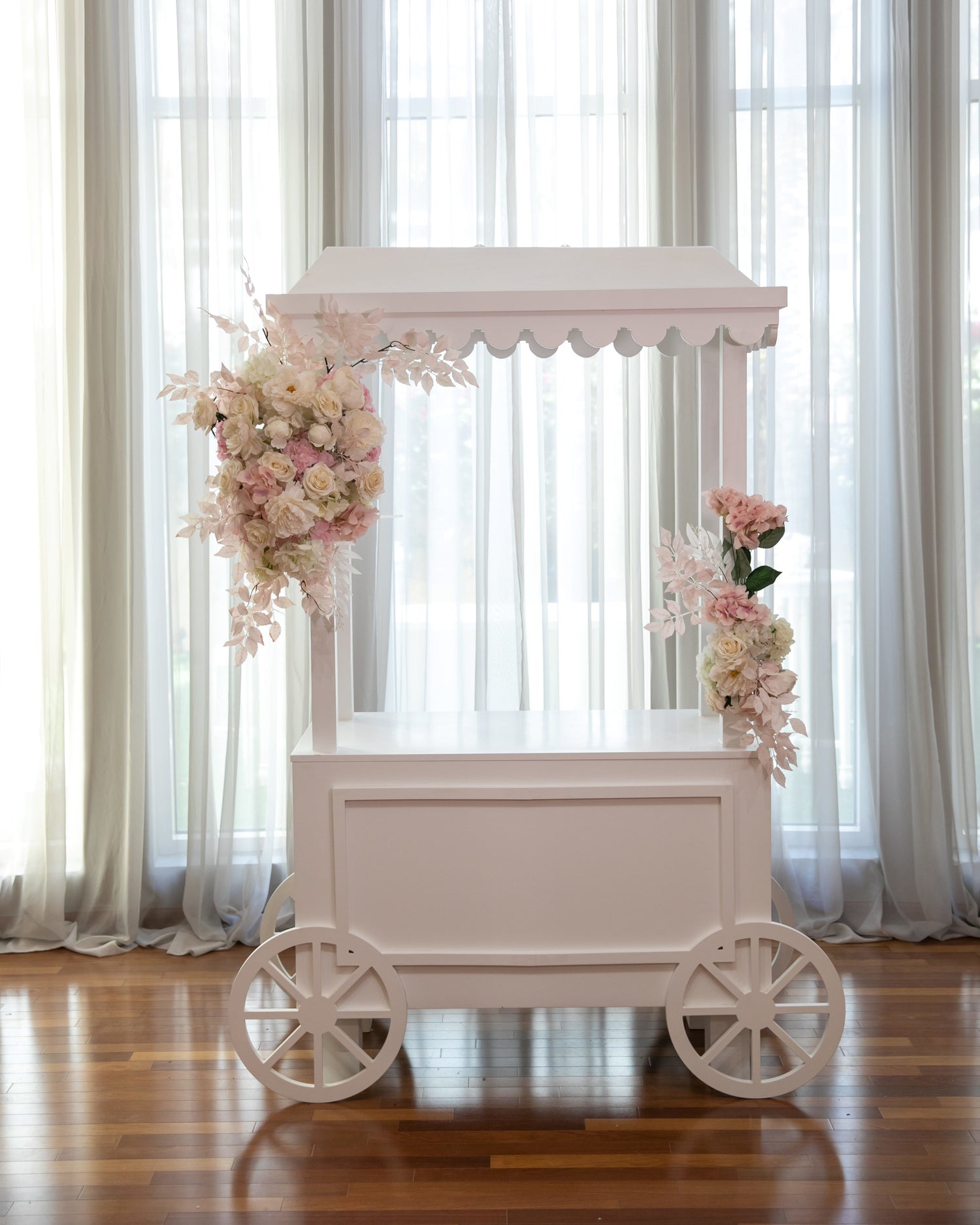 White Dessert Cart with wheels and scalloped edges, adorned with flowers, ideal for event decoration or as a party prop.