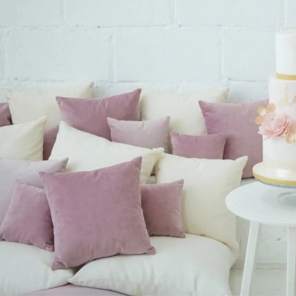CUSHION COVER VELVET on a bench with a two-tiered cake nearby, showcasing premium velvet softness and elegance, perfect for party lounge settings.