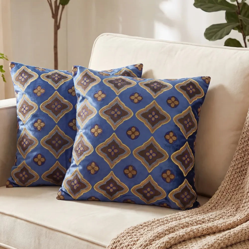 CUSHION PATTERNED BLUE &amp; EARTH TONES on a light sofa with two decorative pillows, featuring a rich blue, brown, and gold motif, perfect for cozy event settings.