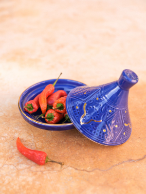 Small Tajine Ceramic Plate with red peppers on it, perfect for serving culinary creations.