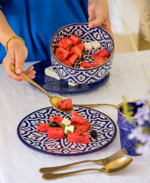 A person holding a bowl of watermelon and a spoon on a Marrakesh Patterned Ceramic Plate.