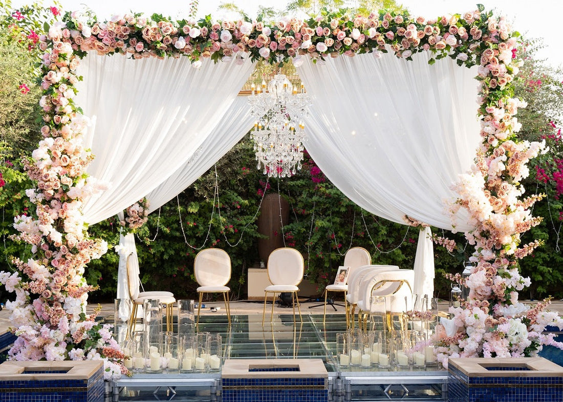 Crystal Chandelier hanging elegantly, enhancing a wedding setup with floral arrangements and gold-legged chairs, perfect for creating a classy event ambiance.