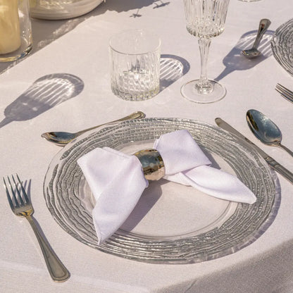 NAPKIN RING - HAMMERED DOME showcased on a clear glass charger plate with a white napkin, part of Party Social&