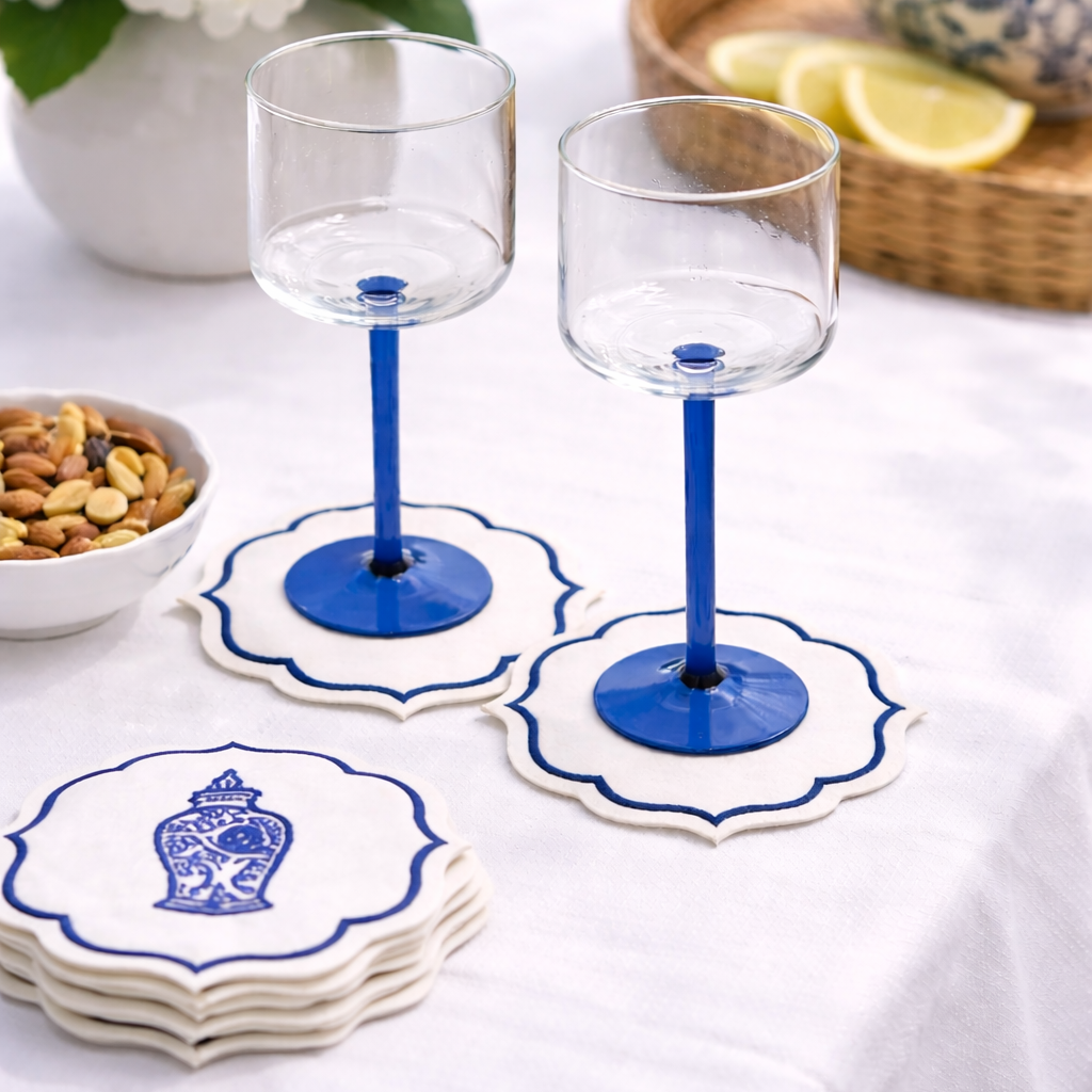 Cobalt-blue stemmed glasses on embroidered linen coasters with a bowl of nuts, part of Party Social&