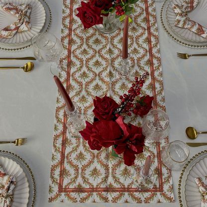 Festive table setting featuring the Holly &amp; Pine Linen Runner, enhancing elegance with patterned napkins, gold flatware, and a rose centerpiece for a luxurious holiday meal.