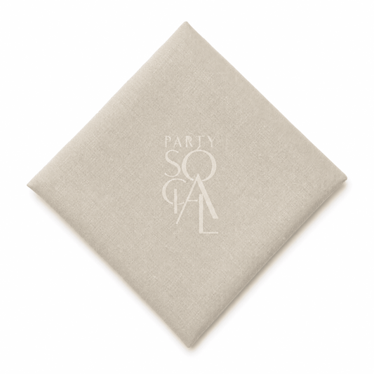 A square beige linen napkin displayed diagonally on a clean white background.