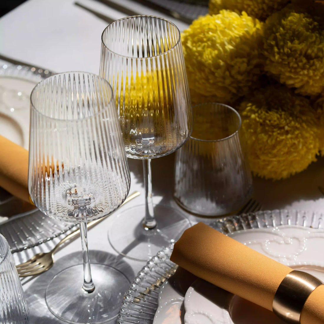 Clear Lined Glassware Collection featured in an elegant table setting with crystal wine glasses, a ridged tumbler, and a mustard-gold napkin, embodying refined event aesthetics.