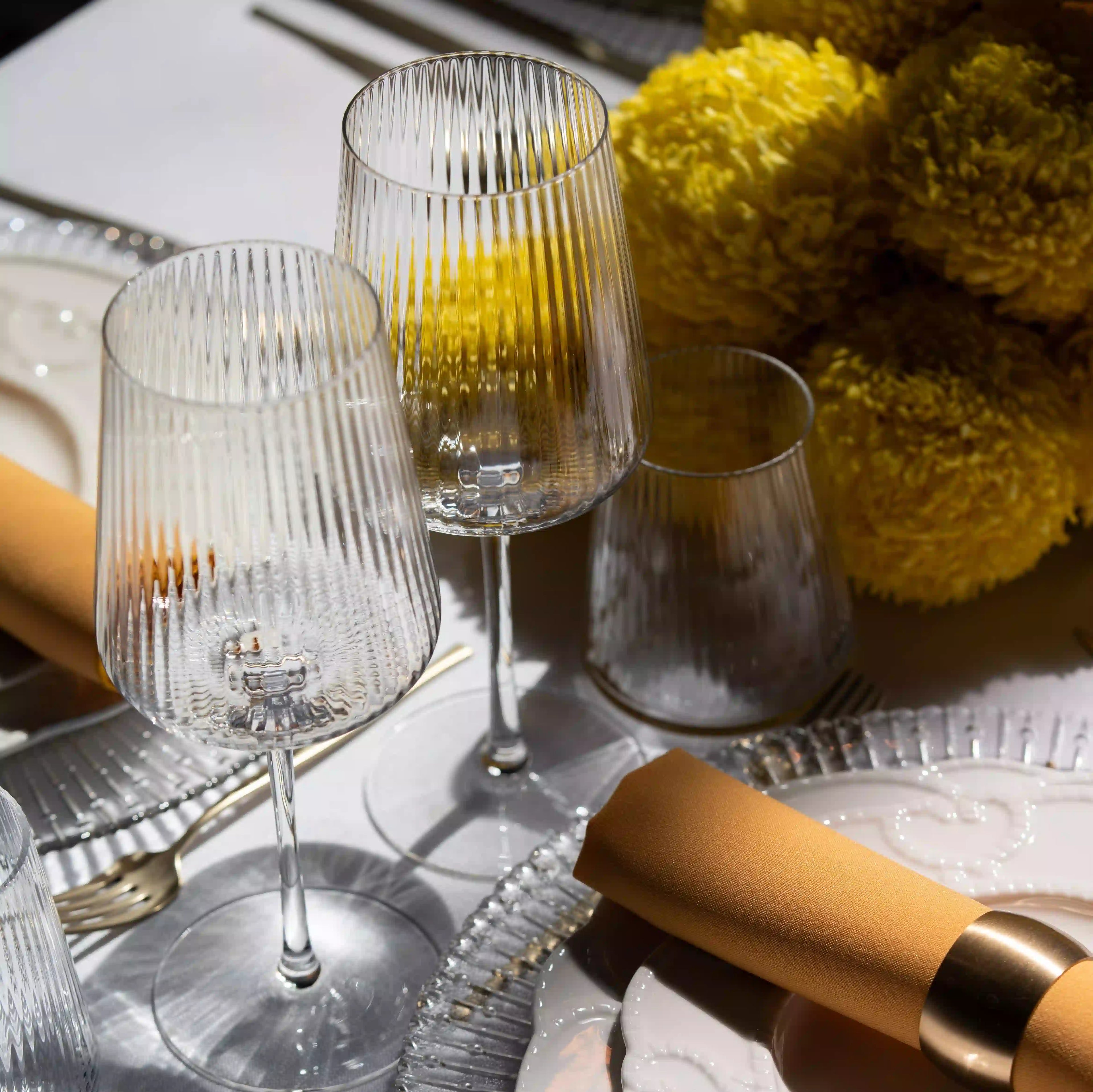 Clear Lined Glassware Collection featured in an elegant table setting with crystal wine glasses, a ridged tumbler, and a mustard-gold napkin, embodying refined event aesthetics.