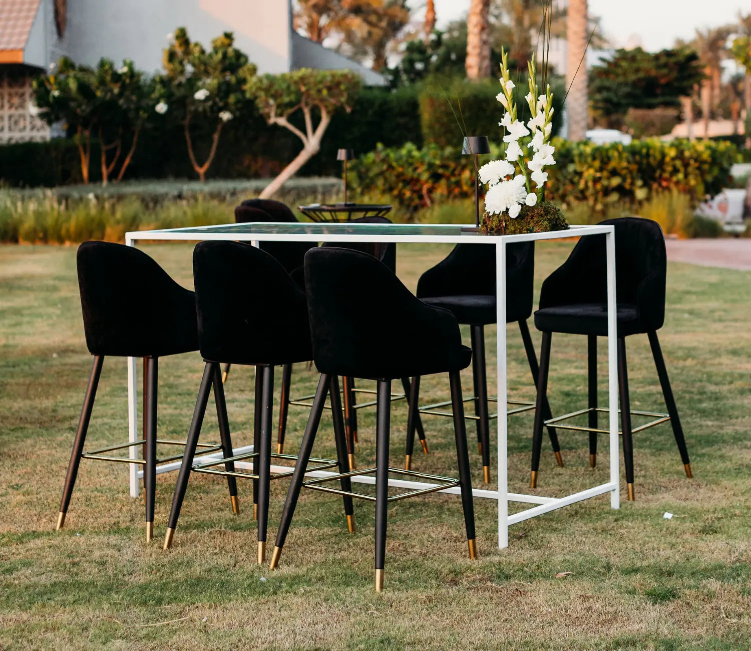 Outdoor setting with a white table and black chairs on grass