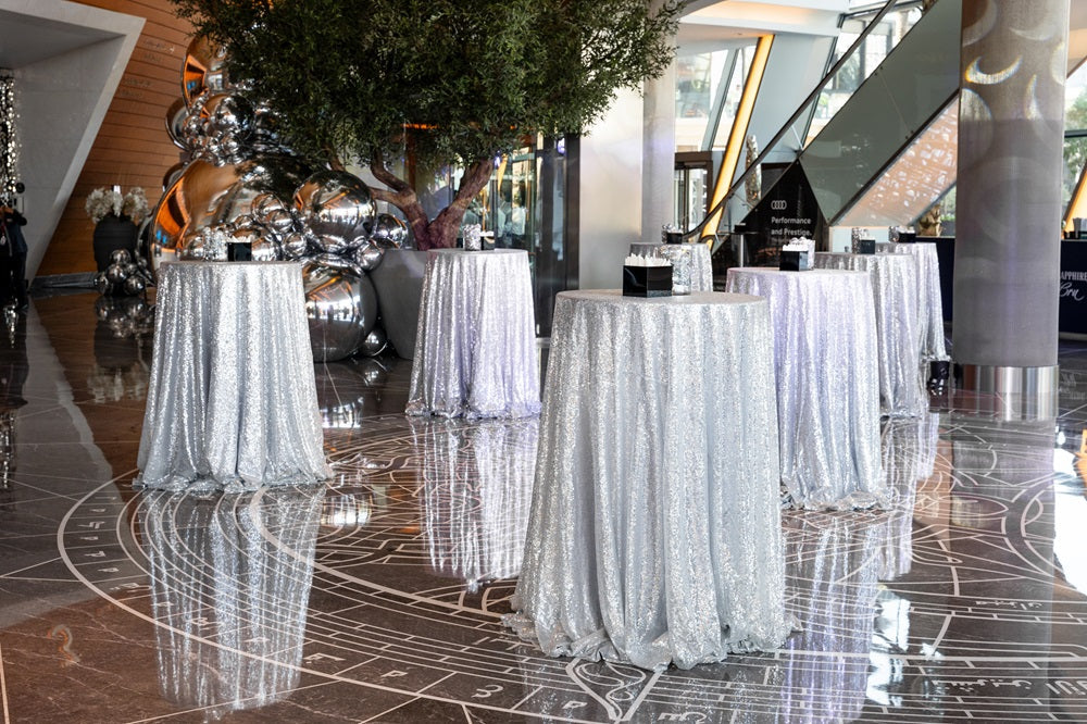 ROUND TABLE COCKTAIL displayed with a silver sequined cloth, highlighting its adaptability for various events, suitable for rental or purchase from Party Social.