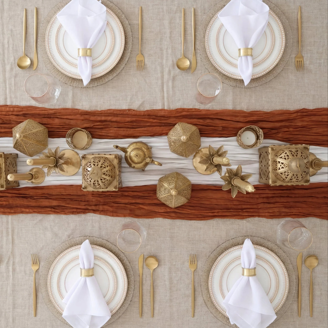 The Golden Desert - Dinner Setup: Elegant table setting for four featuring gold-rimmed plates, gold flatware, stemless glasses, and decorative gold accents on a layered table runner.