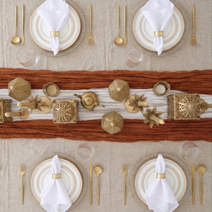 The Golden Desert - Dinner Setup: Elegant table setting for four featuring gold-rimmed plates, gold flatware, stemless glasses, and decorative gold accents on a layered table runner.