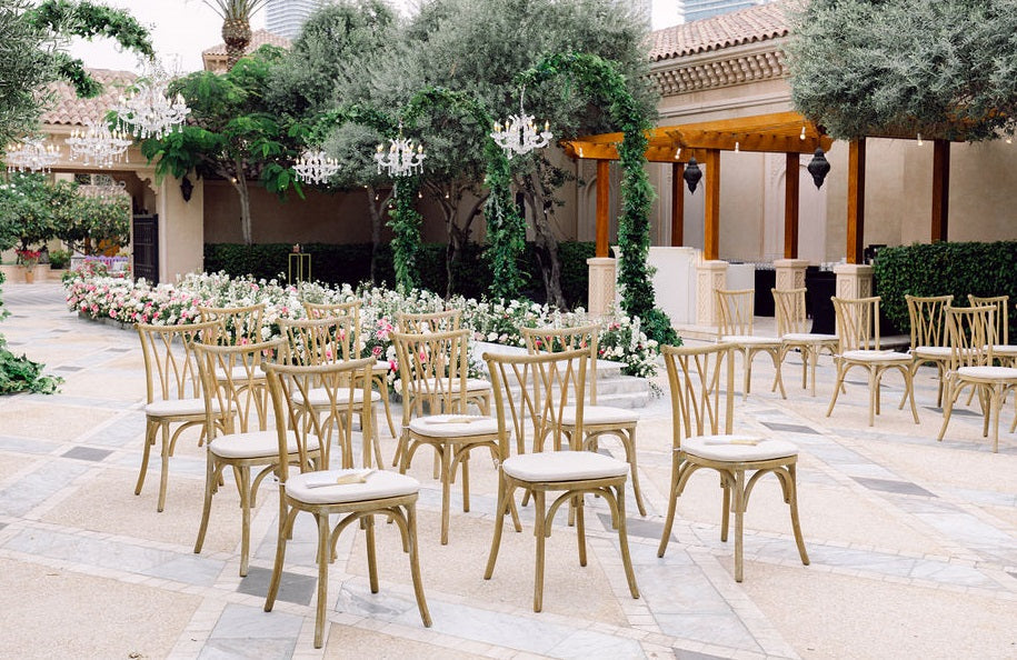 CRISSCROSS CHAIR OAK WOOD: A group of vintage-style oak chairs arranged outdoors, ideal for weddings and corporate functions, showcasing versatility for event settings.