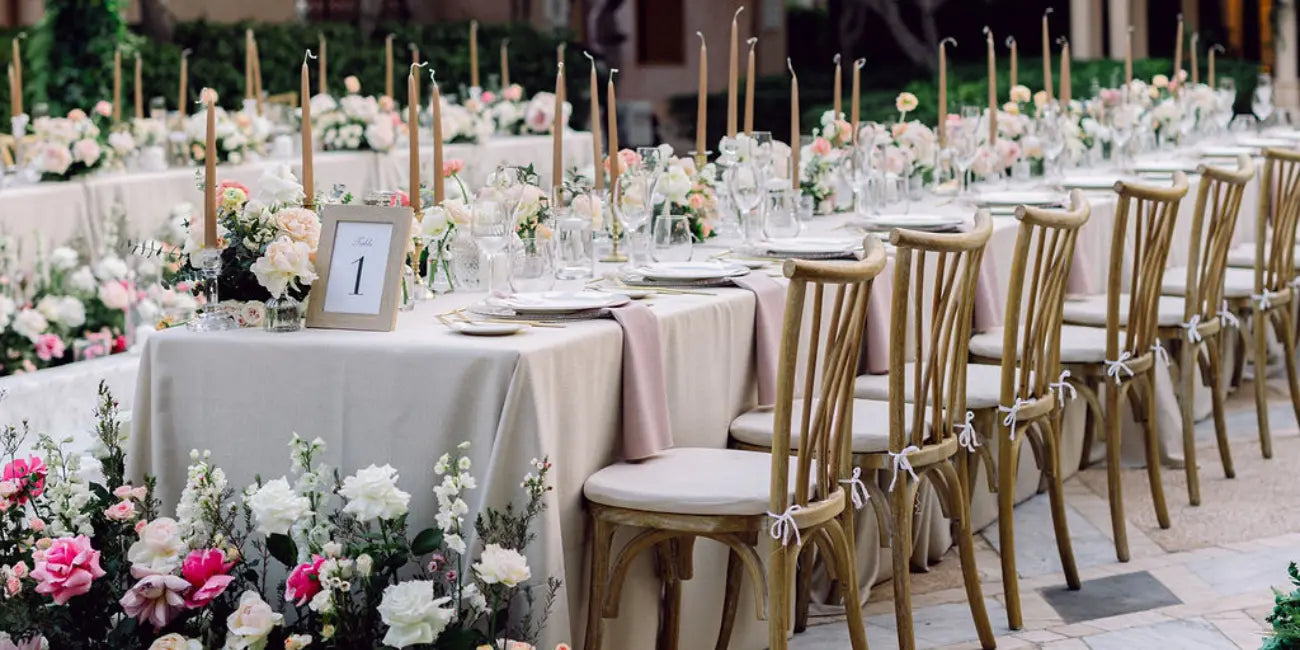 Crisscross wooden chairs with long table covered with linen