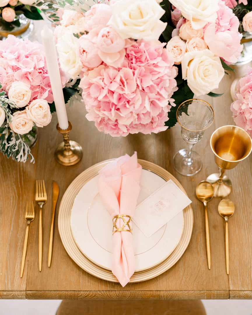 Gold lined glass charger plate elegantly displayed in a floral table setting with wine glass and goldware, perfect for upscale events.