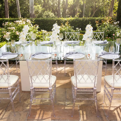 DIAMOND BACK ACRYLIC CHAIR elegantly surrounds a glass dining table set for an upscale event, showcasing its modern geometric design in a garden setting.