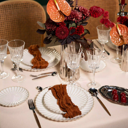 Crystal Paris Glassware Collection elegantly displayed with scalloped plates, burnt orange napkins, and a centerpiece, creating a luxurious tablescape for upscale events.