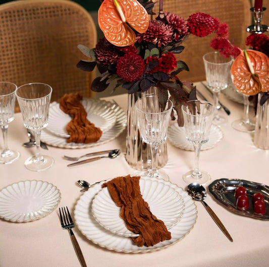 Crystal Paris Glassware Collection elegantly displayed with scalloped plates, burnt orange napkins, and a centerpiece, creating a luxurious tablescape for upscale events.