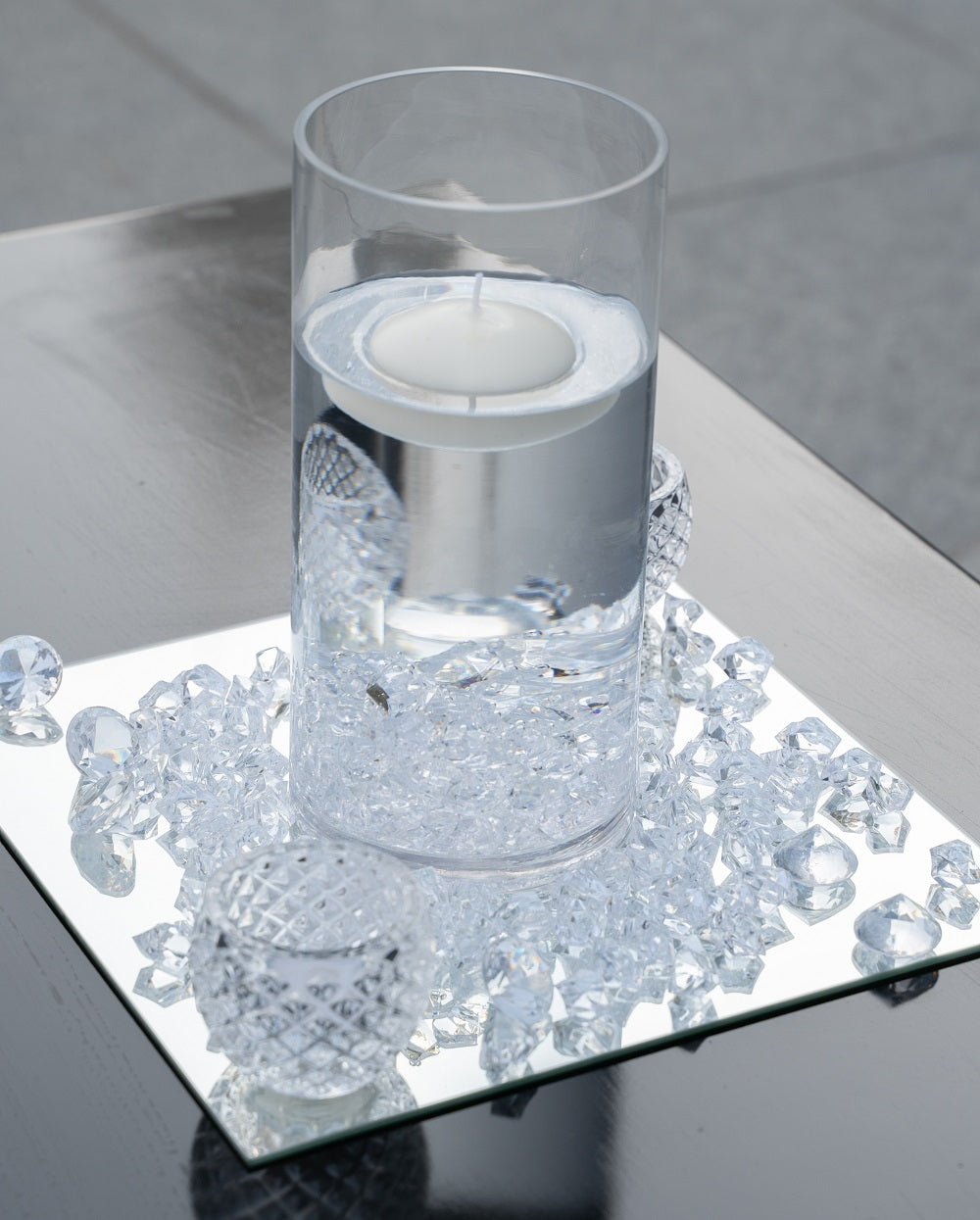 ACRYLIC MIRROR CENTERPIECE SQUARE displayed with a candle in a glass vase on a tray, ideal for elegant event decorations.