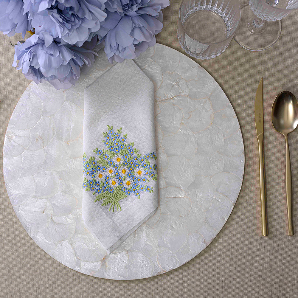 Round Shell Placemat with flowers, glasses, knife, and glass on table setting.