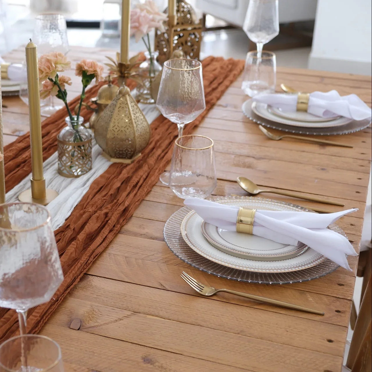 The Noor Royale - Dinner Setup features a wooden table with elegant place settings, gold cutlery, and decorative lanterns, perfect for a sophisticated party gathering.